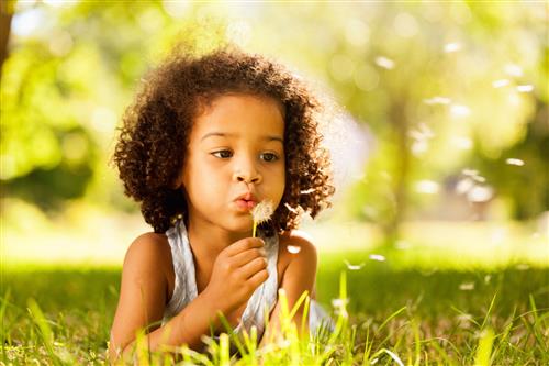 girl blowing dandelion fuzz 